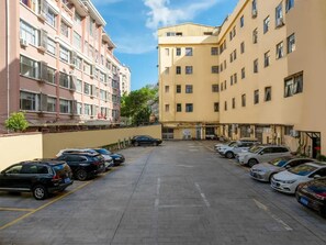 A parking lot with multiple cars parked in rows, adjacent to a building with multiple floors and balconies.