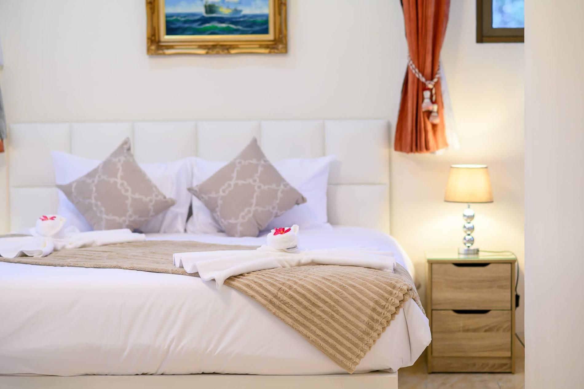A neatly made bed with pillows, a bedside lamp, and a framed picture on the wall.