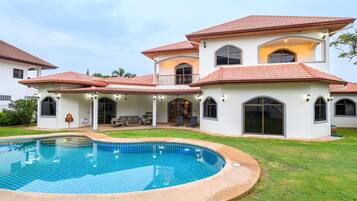 Una casa grande con piscina, varios balcones y un patio cubierto.
