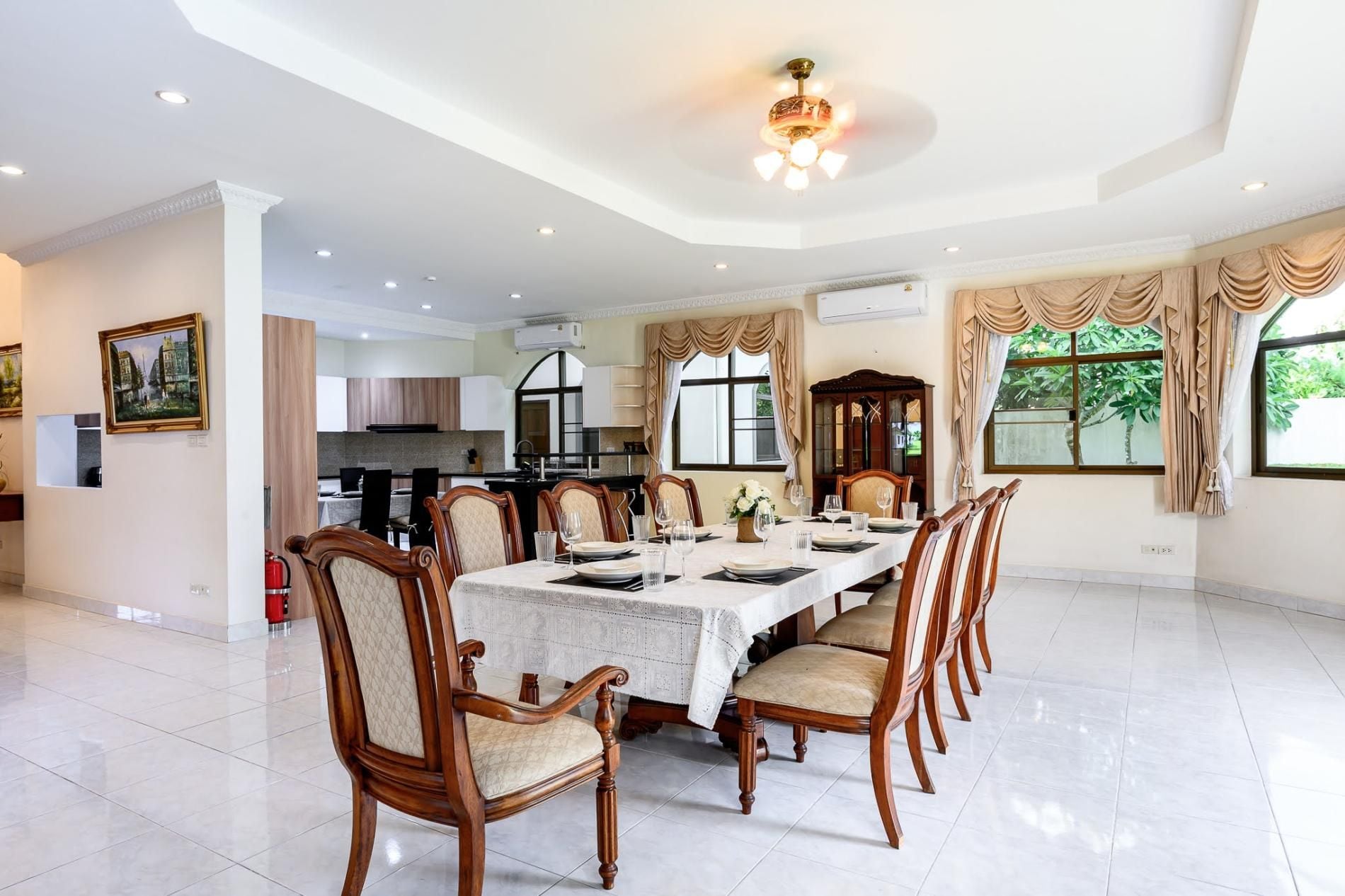 Comedor con una mesa larga dispuesta para seis personas, rodeada de sillas de madera con asientos acolchados.