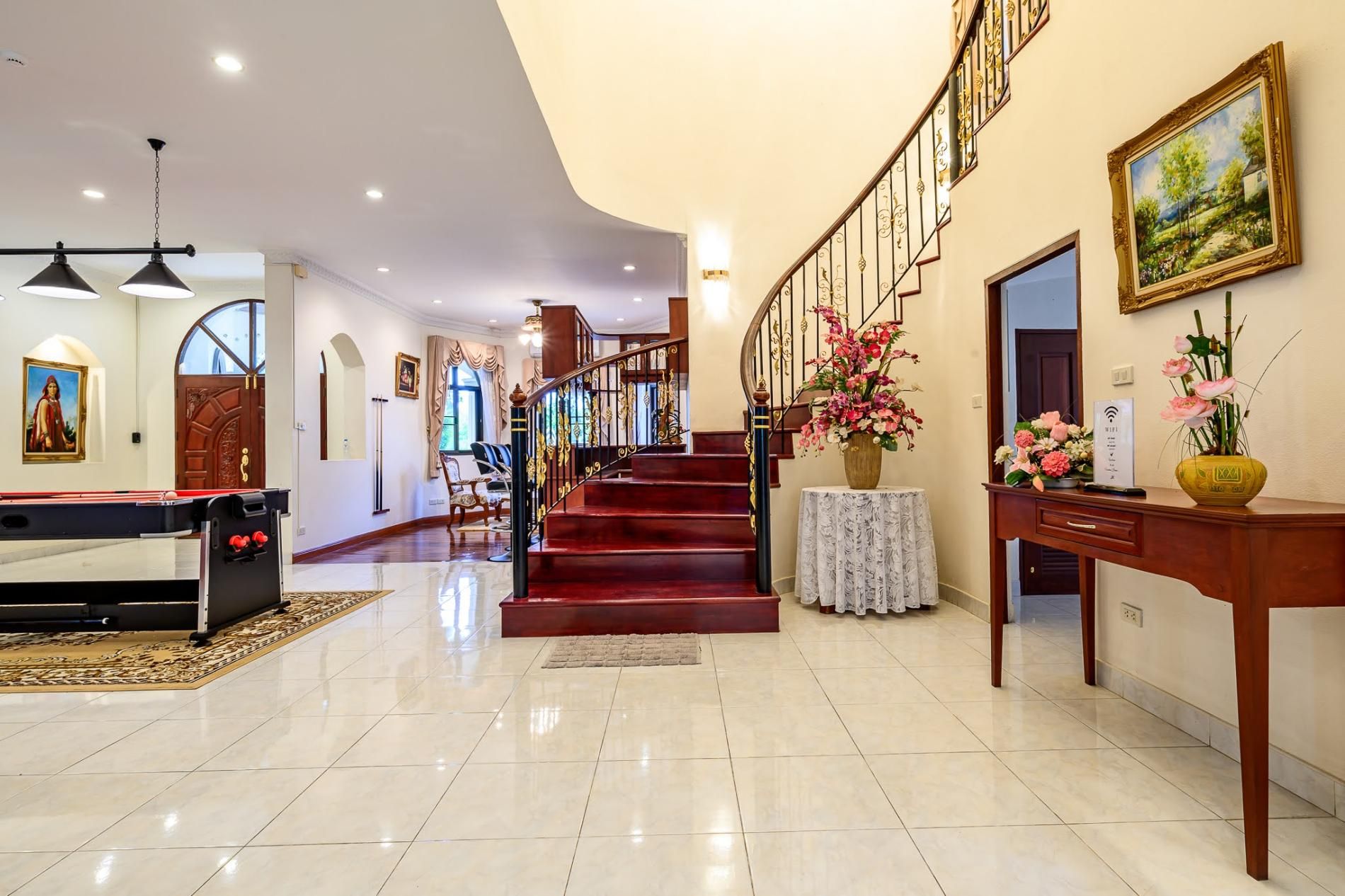 A spacious lobby with a pool table, a staircase, and a reception desk.