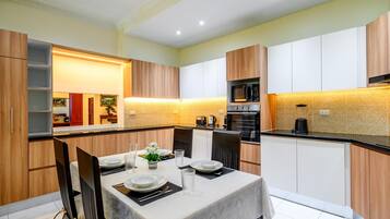 A modern kitchen with a dining area, featuring a table set for four, a microwave, and a coffee maker.