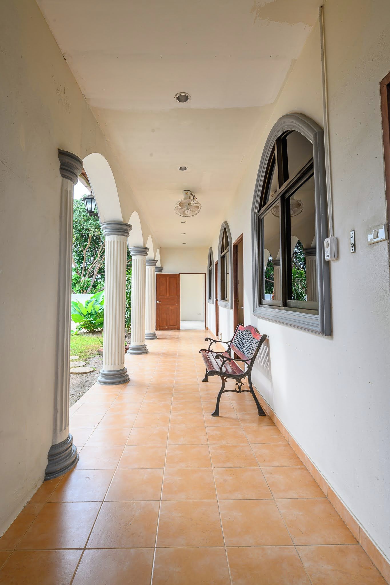 A corridor with columns, a bench, and a door leading to a room.