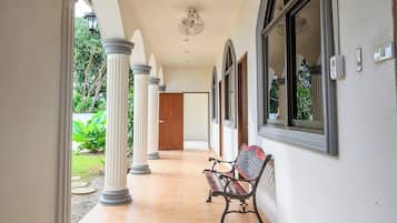 A corridor with columns, a bench, and a door leading to a room.