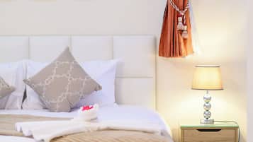Una cama bien hecha con almohadas, una lámpara de noche y una mesita de noche de madera con cajones.