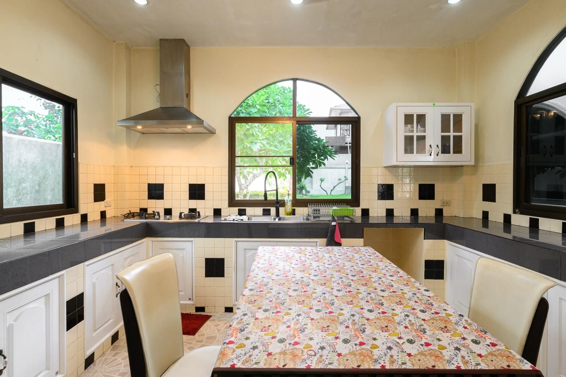 A kitchen with a dining table, cabinets, a window, and a stove.