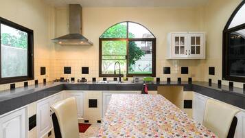 A kitchen with a dining table, cabinets, a window, and a stove.