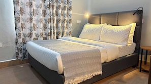 Un dormitorio moderno con cama, cortinas y una lámpara de noche.