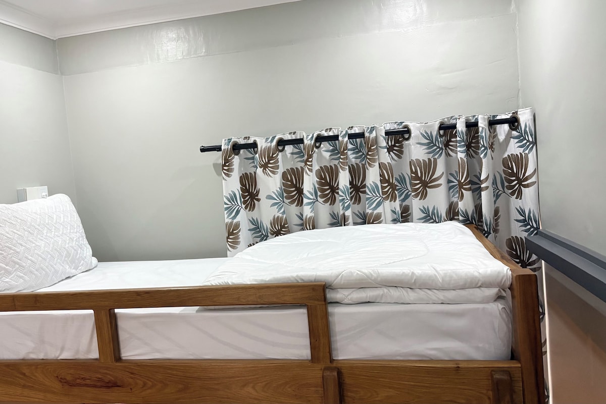 A single bed with a wooden frame, white bedding, and a pillow.