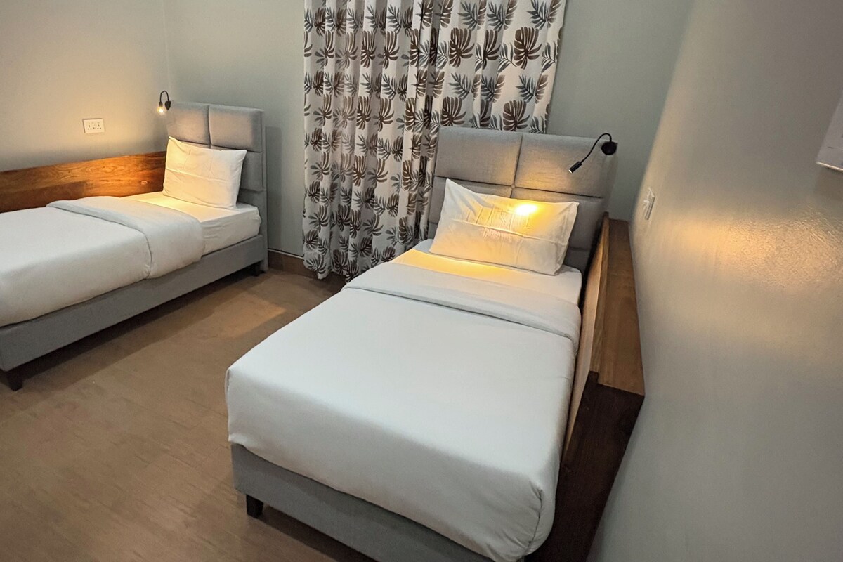Two single beds with headboards, a wooden headboard bed, and a curtain with a leaf pattern.