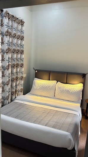 A bed with a headboard, pillows, and a blanket. - Siku Lodge (Arusha)