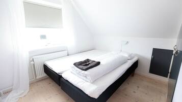 A single bed with white bedding, a black headboard, and a brown towel.