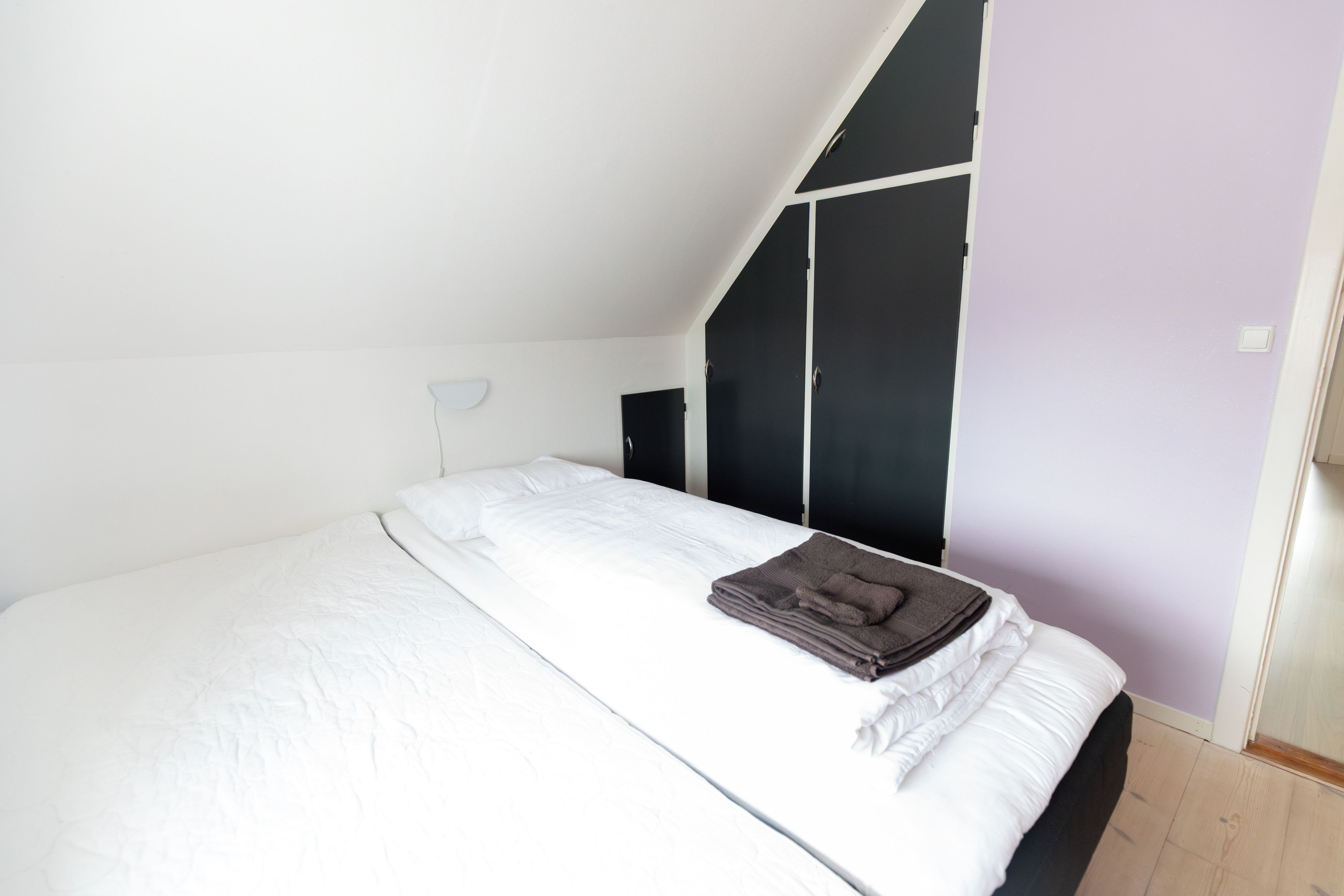 Een slaapkamer met een bed, een kledingkast en een schuine kap.