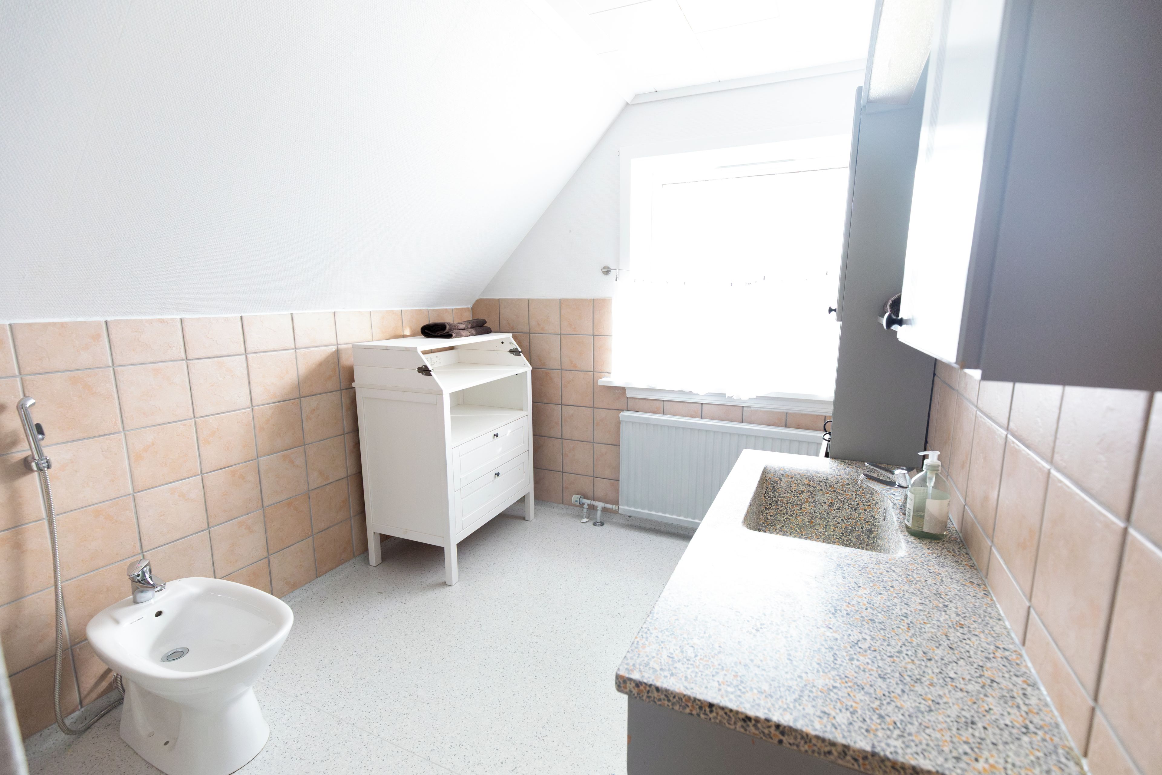 A small, bright bathroom with a toilet, bidet, and a sink.