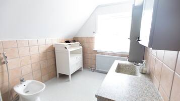 A small, bright bathroom with a toilet, bidet, and a sink.
