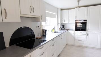 Una cocina moderna con armarios blancos, una placa de cocción por inducción negra y un horno empotrado.