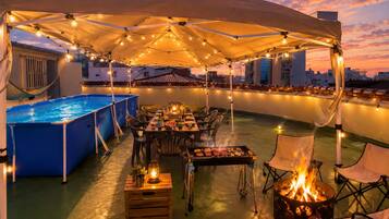An outdoor rooftop terrace with a pool, dining area, and a fire pit.