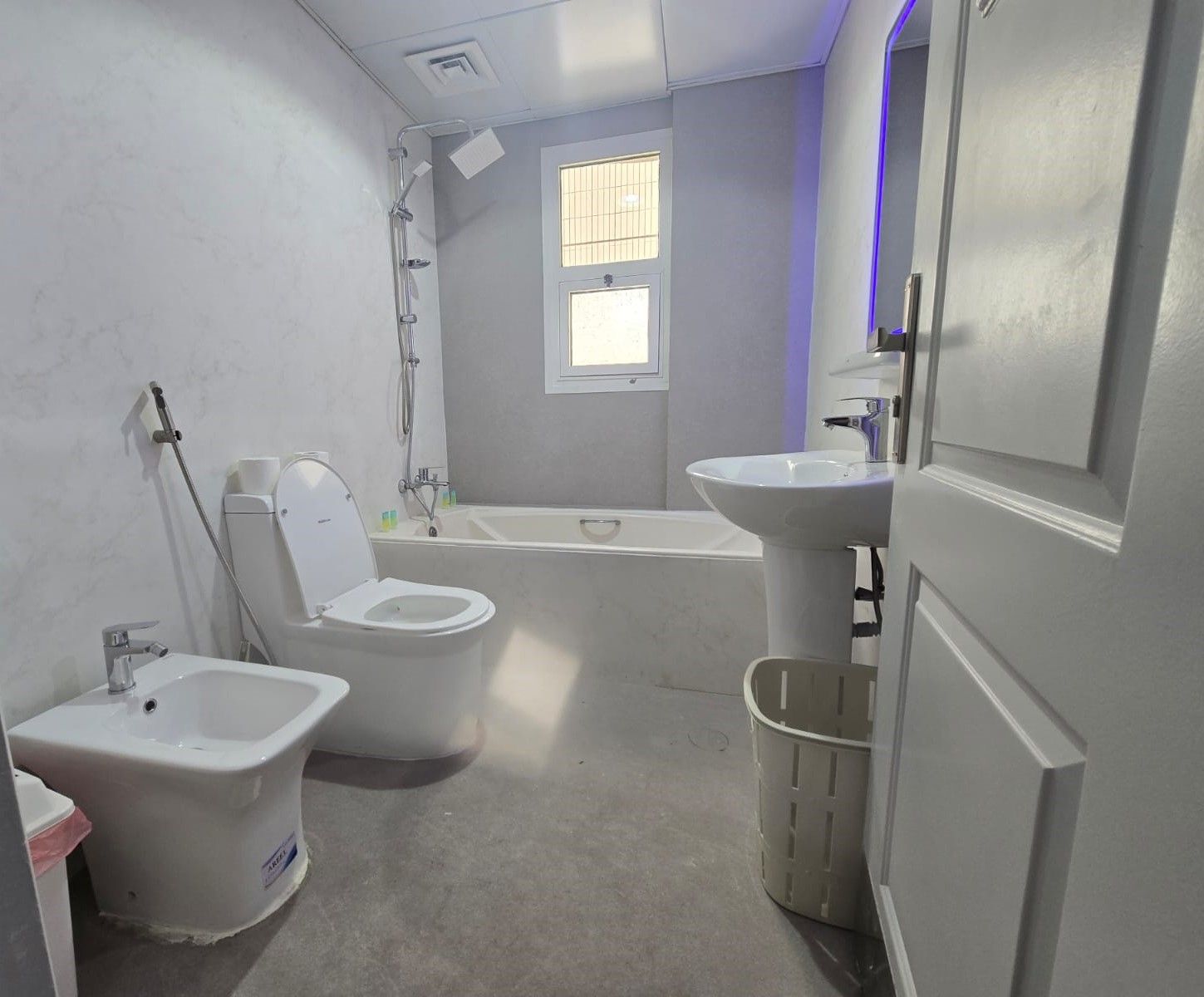 A bathroom with a toilet, bidet, bathtub, and sink.