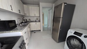 Una cucina moderna con elettrodomestici in acciaio inossidabile, mobili chiari in legno e una lavatrice integrata.