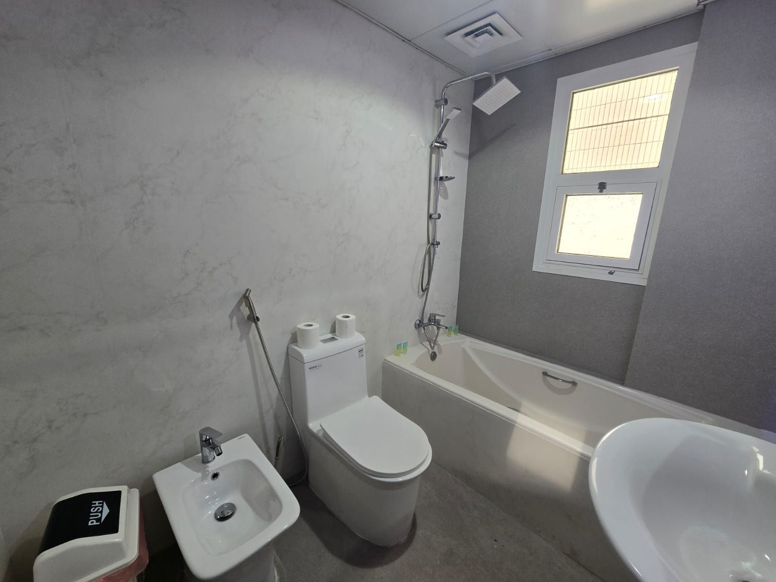 A bathroom with a toilet, bidet, sink, and bathtub.