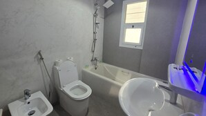 Un bagno con WC, bidet, lavandino, vasca e una finestra.