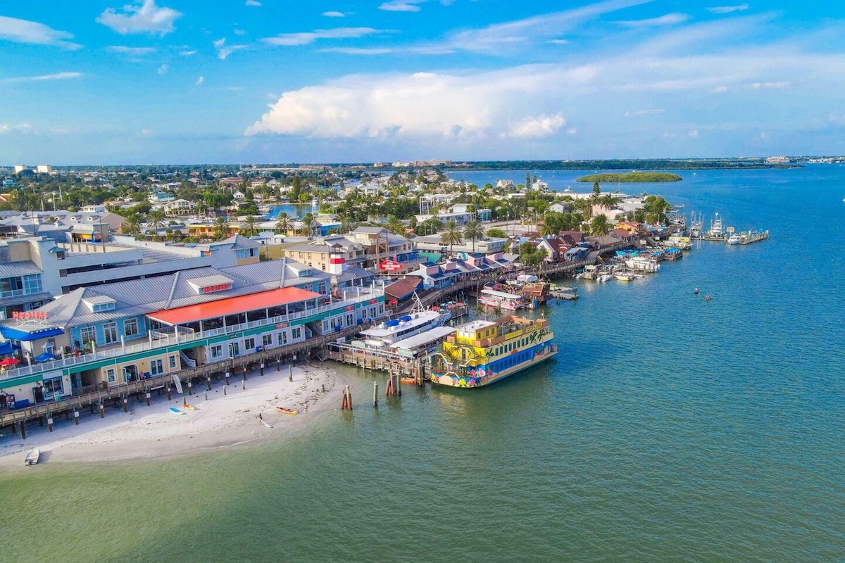A coastal town with a pier, waterfront buildings, and a colorful boat docked at the pier.