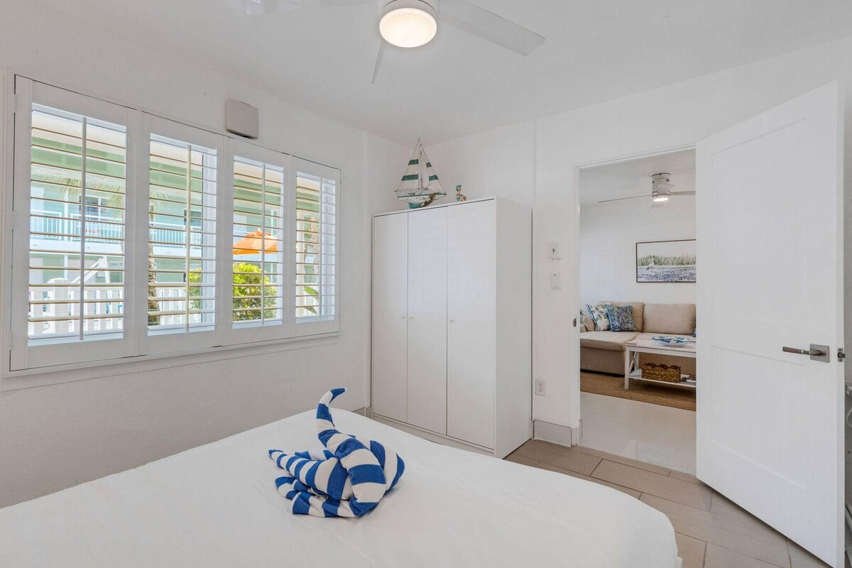 Un dormitorio con cama, armario, ventana con persianas y vista al exterior.