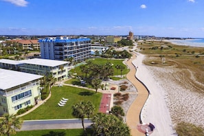 Un hotel frente al mar con varias construcciones, una playa y cielo despejado.