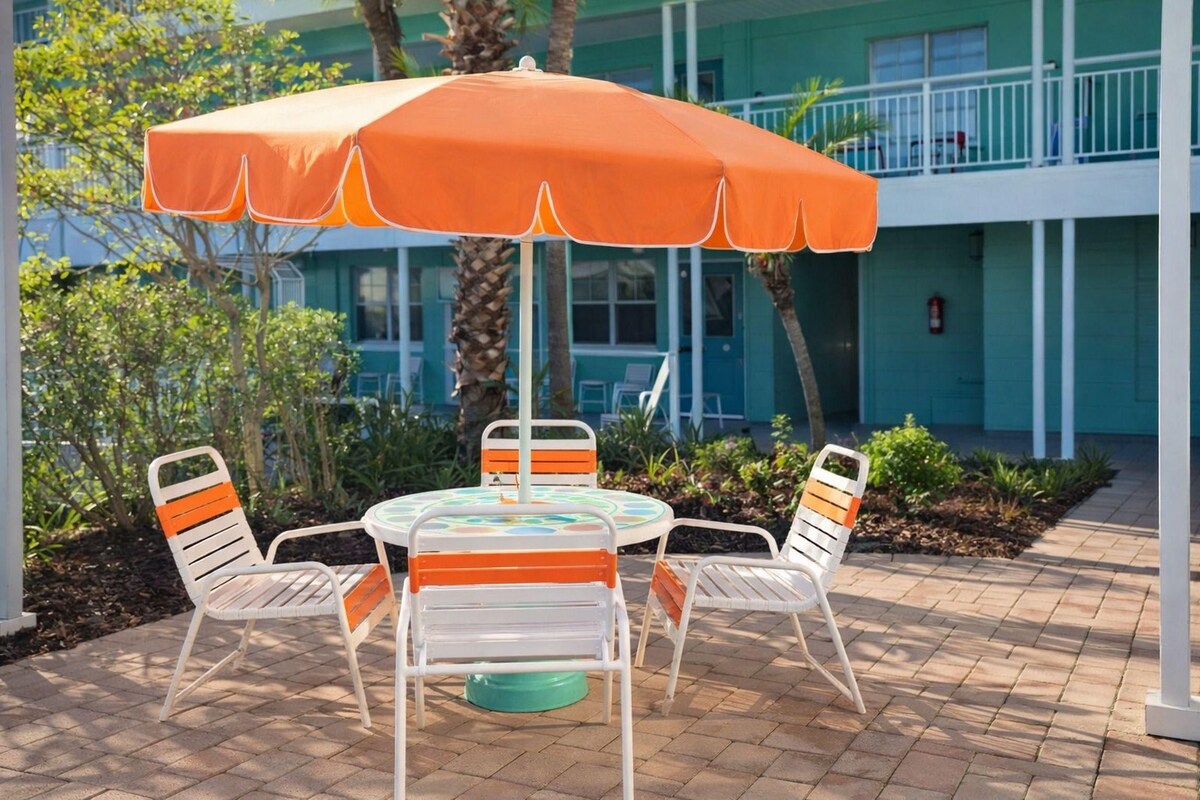 A patio with a round table, four chairs, and a large umbrella.