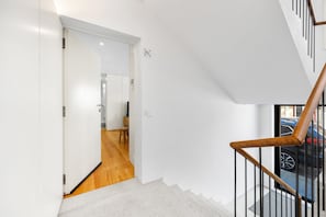 Ein modernes Interieur mit einer Treppe, Holzböden und Blick auf parkende Autos vor dem Gebäude.