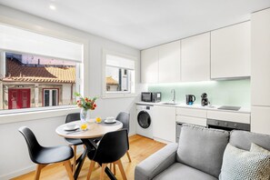 Um espaço de estar compacto com área de refeições, sofá, máquina de lavar e cozinha compacta.