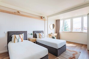 A hotel room with two beds, a bedside table, a mirror, and a window with a view. - Duplex with Private Terrace and A/C in Cascais (Cascais)