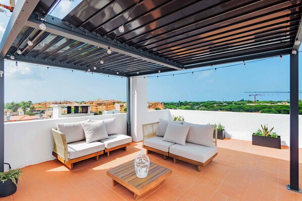 A covered outdoor seating area with two sofas and a coffee table, overlooking a cityscape. - Duplex with Private Terrace and A/C in Cascais (Cascais)