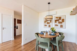 Uma área de refeições com uma mesa redonda, quatro cadeiras e um lustre.