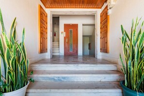 A hotel entrance with a marble staircase, wooden doors, and potted plants. - Duplex with Private Terrace and A/C in Cascais (Cascais)