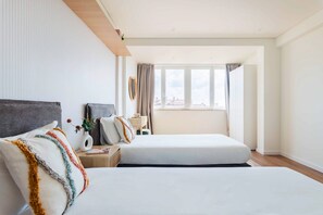 A hotel room with two beds, a window with curtains, a bedside table with a lamp, and a view of the cityscape. - Duplex with Private Terrace and A/C in Cascais (Cascais)