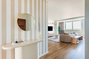 A modern living room with a large round mirror, a sofa, a coffee table, and a television. - Duplex with Private Terrace and A/C in Cascais (Cascais)