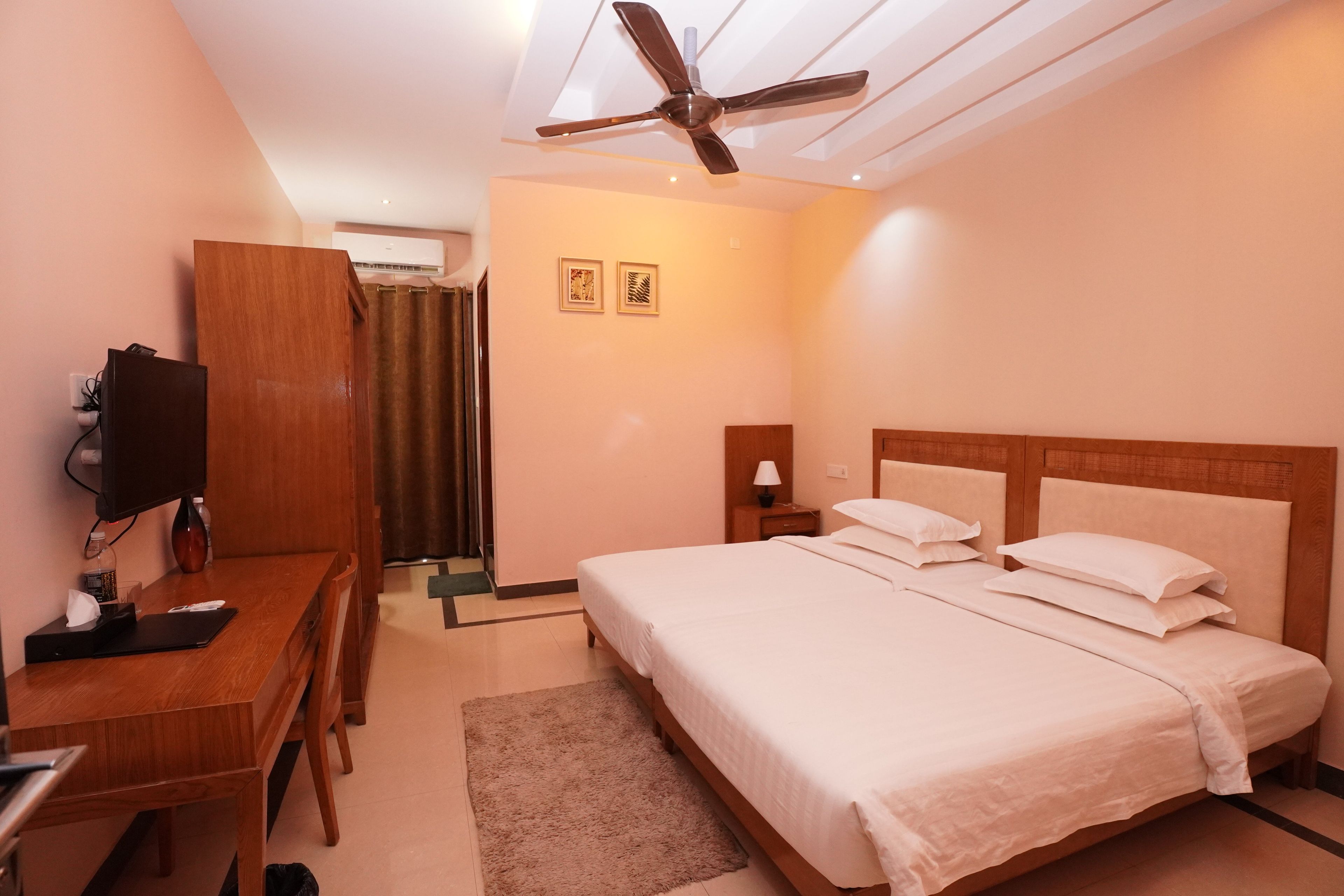 A hotel room with a bed, desk, chair, and a ceiling fan.
