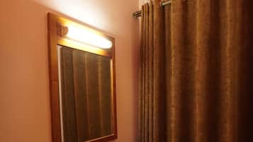 Un baño con espejo, unidad de aire acondicionado, mueble de madera y espejo redondo en el suelo.