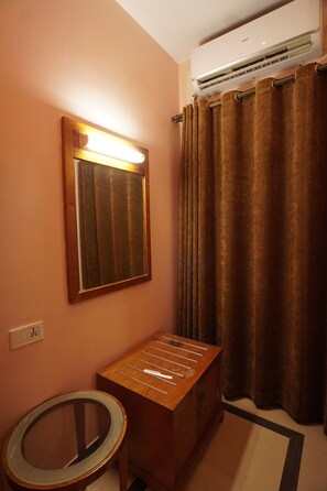 Un baño con espejo, unidad de aire acondicionado, mueble de madera y espejo redondo en el suelo.
