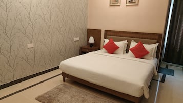 Una habitación de hotel con una cama, una mesita de noche, una lámpara y un papel tapiz con motivos de árboles.