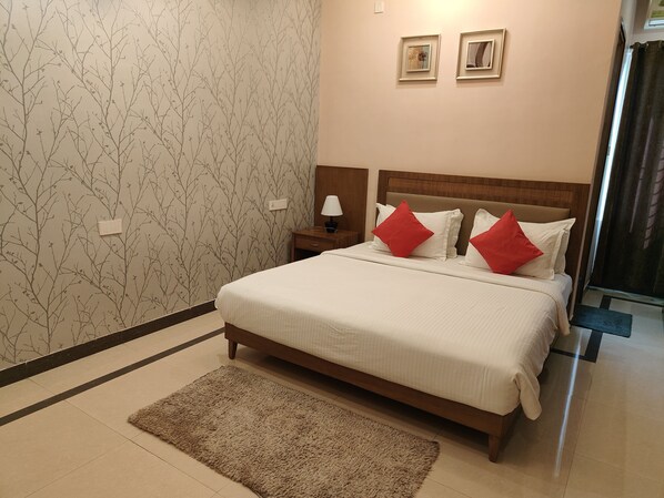 Una habitación de hotel con una cama, una mesita de noche, una lámpara y un papel tapiz con motivos de árboles.