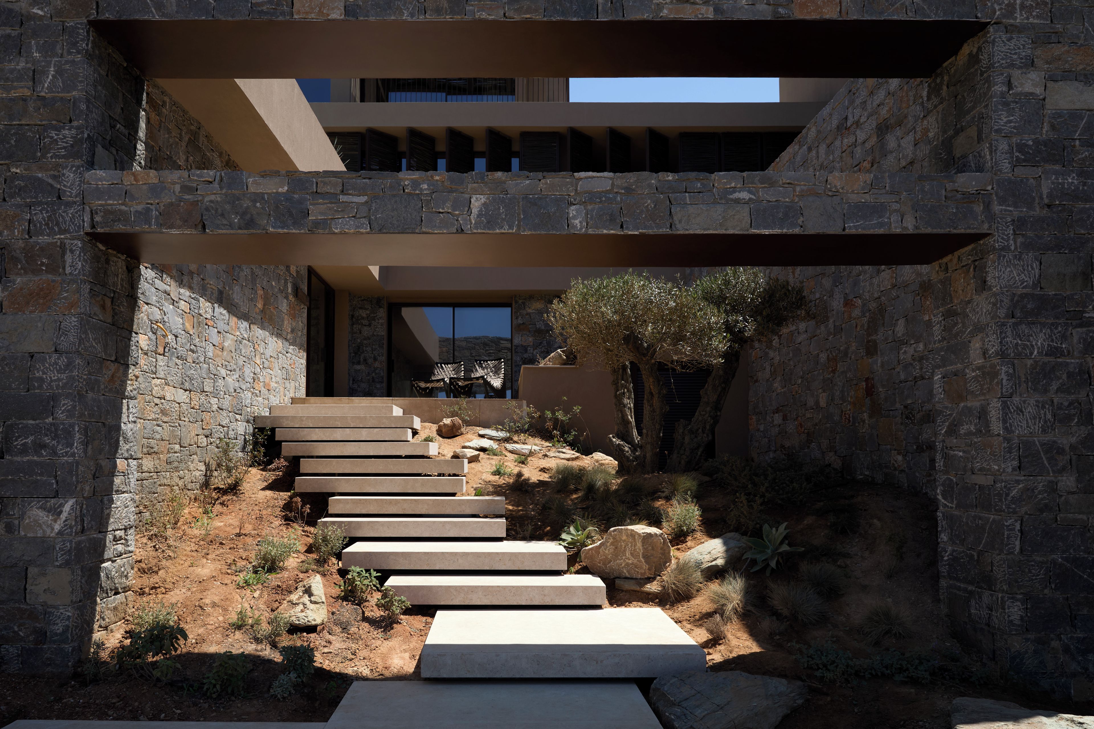 Un edificio moderno con fachada de piedra, un conjunto de escalones exteriores y vistas del paisaje circundante.