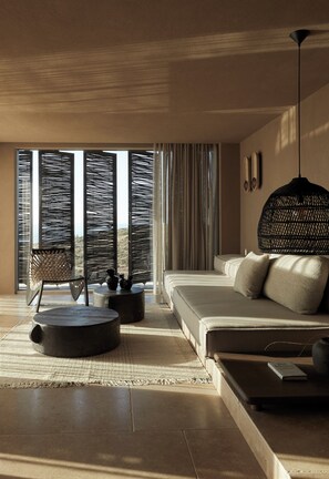 A modern bedroom with a large bed, a hanging light fixture, and a view through the window.