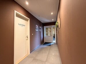 A hallway with a door labeled 'LAUNDRY' and a wall-mounted clock.