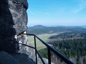 Ein felsiger Klippenabsatz mit Metallgeländer mit Blick auf ein bewaldetes Tal.