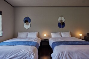 Habitación de hotel con dos camas, cada una con ropa blanca y un detalle azul. Hay apliques de luz en las paredes a ambos lados de las camas.