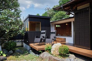 Un espacio moderno para sentarse al aire libre con terraza de madera, dos sillas plegables y una mesita.