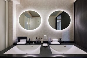 A modern bathroom with two sinks, a mirror, and toiletries.