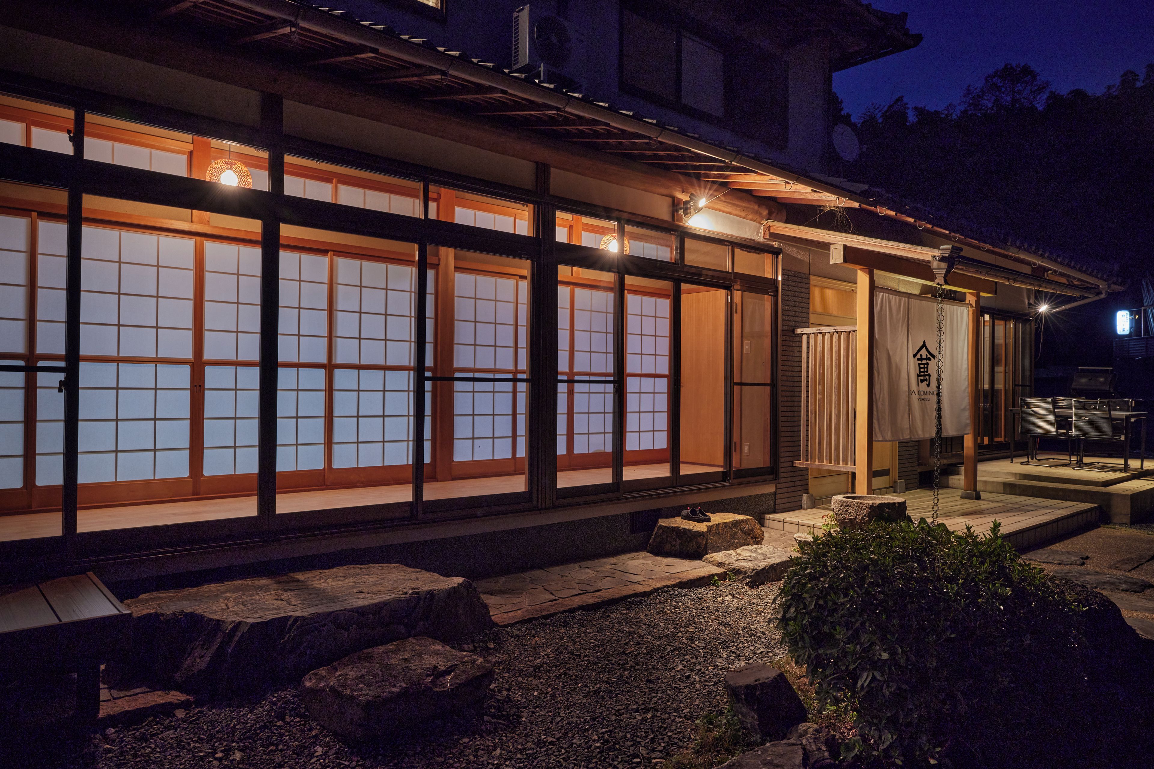 Un edificio japonés tradicional con grandes puertas correderas y un sendero de piedra que conduce a la entrada.